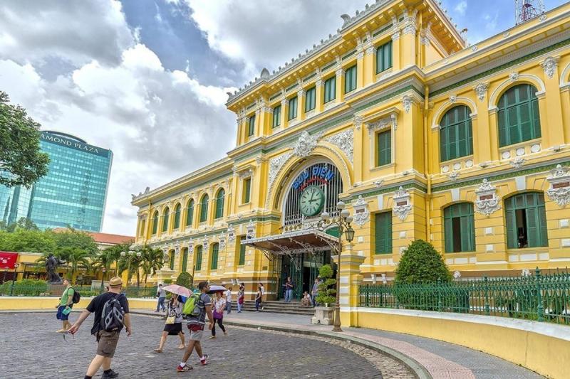 A photograph showing visitors inside the Central Post Office, some taking photos, others looking at the architecture or maps, highlighting the atmosphere of a popular tourist spot. Capture the blend of functional post office and visitor attraction.
